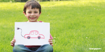 Child holding a drawing of an electric car