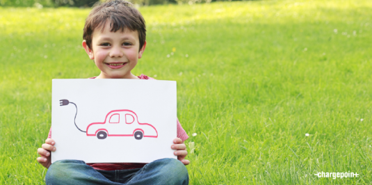 Child holding a drawing of an electric car