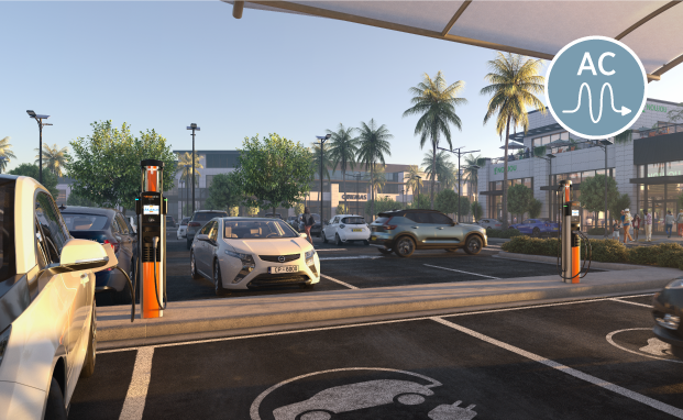Electric vehicle charging stations in a parking lot with palm trees and a mall in the background.