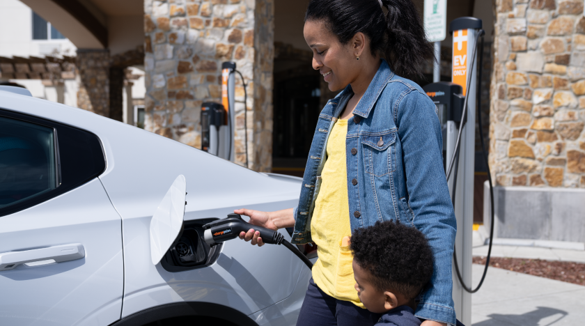Mother with child charging an electric vehicle at a public charging station. Mother with child charging an electric vehicle at a public charging station.