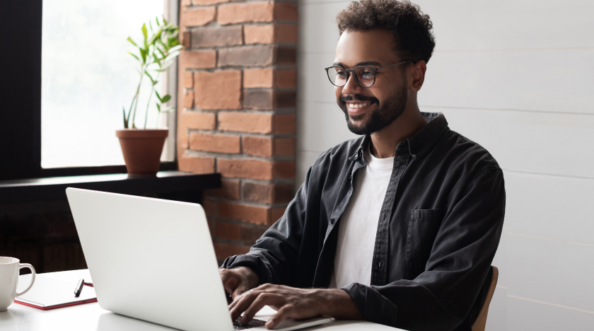 Man smiling while working on a laptop. Man smiling while working on a laptop.