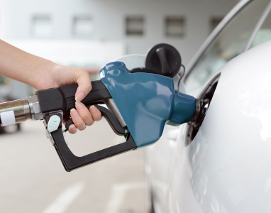 Hand refueling a white car at a gas station.