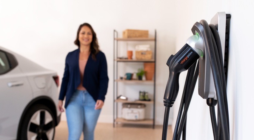 A woman standing next to a ChargePoint Home Flex charging station in a garage.